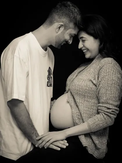 A black and white studio portrait that feels incredibly warm and intimate. The casual outfits and the close, gentle pose make this a beautiful, authentic image of impending parenthood.