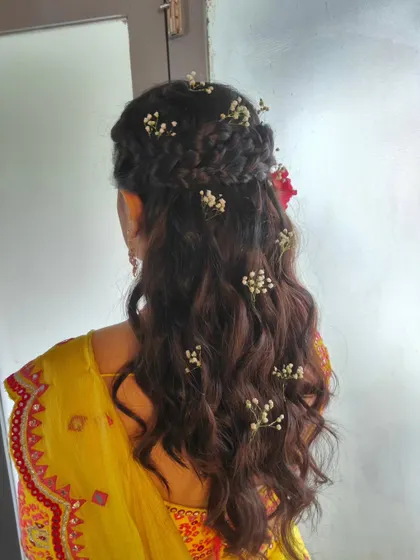 A back view of a braided half-updo for a Haldi ceremony, adorned with baby's breath. This style is both romantic and practical.