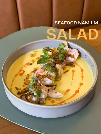 Our Seafood Nam Jim Salad, a dish inspired by travels to Thailand. It features tender seafood in a zesty dressing over a smooth corn and coconut panna cotta.