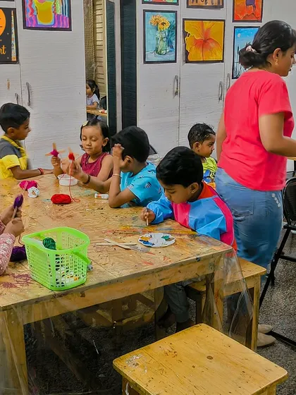 A wide view of our yarn craft session. An instructor guides the students as they wrap colorful yarn, creating their own little masterpieces.