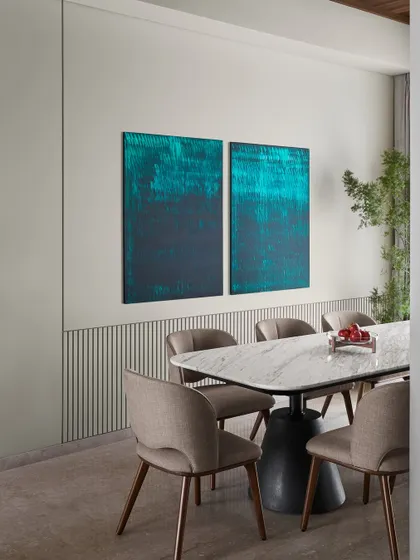 The dining area is anchored by a striking teal diptych artwork, painted by our founder. This personal touch adds bold color and energy, complementing the 9-foot marble and steel dining table.
