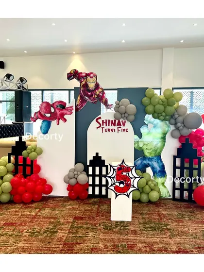 An action-packed Superhero-themed birthday backdrop. It features dynamic cutouts of Iron Man, Spider-Man, and the Hulk against a city skyline, perfect for a young hero's celebration.