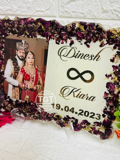 This 9x12 inch resin frame features a zigzag border made of preserved purple varmala petals and gold flakes. The design includes a photo and the couple's names.