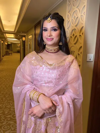 A whimsical and dreamy look. The makeup is soft and ethereal, with a focus on glowing skin and a hint of pink, complemented by a beautiful maang tikka.