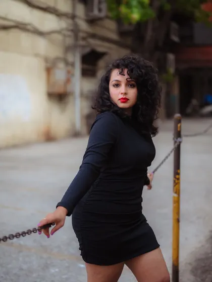 A powerful portrait using an industrial chain as a prop. The gritty background and the model's strong pose create a bold and impactful fashion statement.
