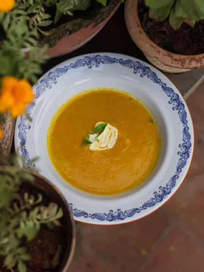 A rustic pumpkin or carrot soup served in a traditional bowl, perfect for a cool evening.