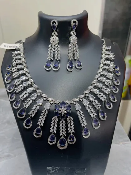For a touch of classic elegance, this stunning necklace and earring set is a perfect choice. The intricate design combines brilliant clear crystals with deep sapphire-blue stones, making it an ideal rental for your reception or a formal evening party.