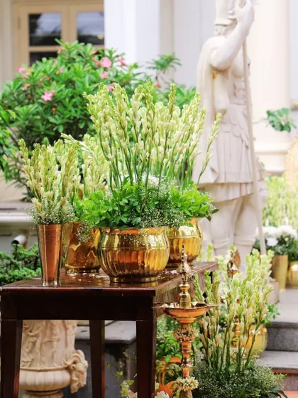 Elegance in the details. For this daytime event, I used arrangements of white tuberoses in gleaming golden pots, complemented by a traditional brass lamp, to create a feeling of serene and sophisticated welcome.