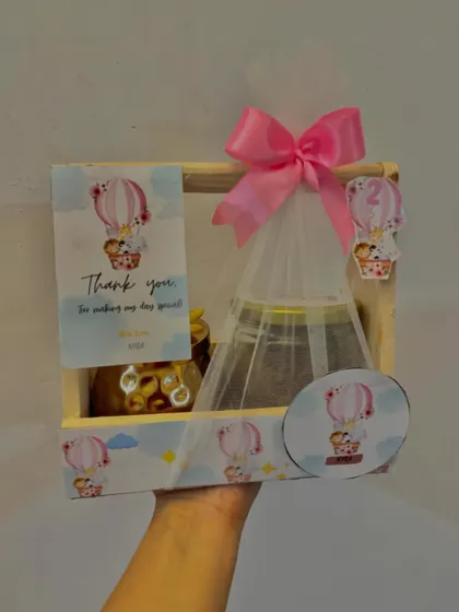 This hot air balloon themed hamper is perfect for a little one's birthday. The wooden crate holds two jars of treats and is decorated with a personalized tag and a cute die-cut balloon.