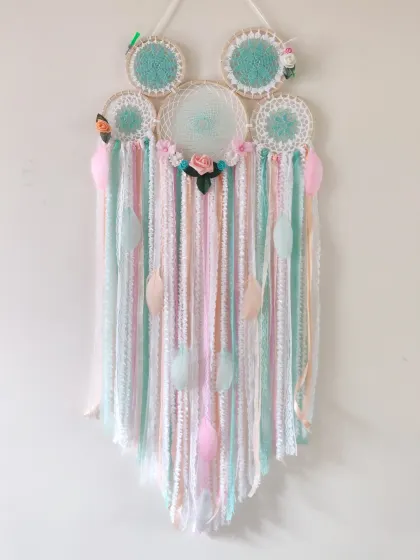 A beautiful cluster dreamcatcher in candy-colored hues of mint, peach, and pink. The floral accents and delicate ribbons make this a truly dreamy piece for a nursery or bedroom.