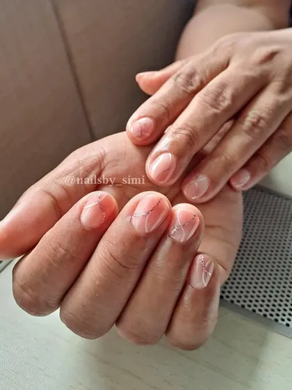 Sweet, simple, and elegant. This design on short, natural-looking nails features a sheer pink base with delicate silver glitter lines for a touch of sparkle.
