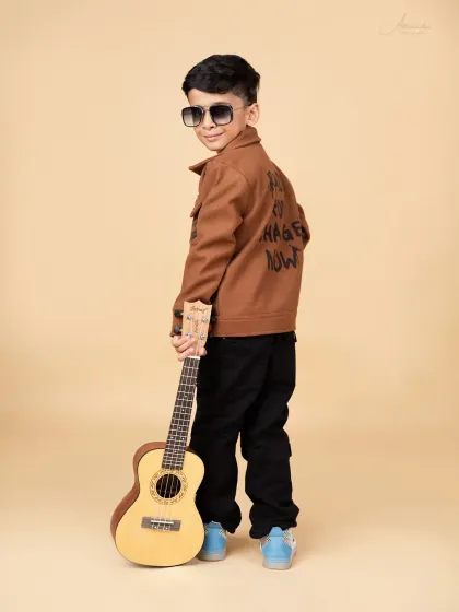 A cool over-the-shoulder look from our little model, showing off his stylish jacket and guitar.