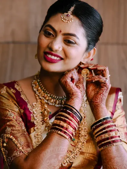 A classic getting-ready shot. The bride is putting on her earring, and her smile shows she's excited and happy with her look.
