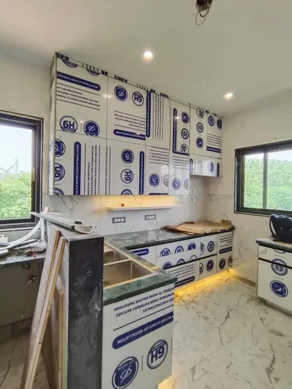 This shot captures the kitchen as it comes to life. The under-cabinet lighting is on, and the marble-patterned backsplash is in place, with the cabinets awaiting their final unwrapping.