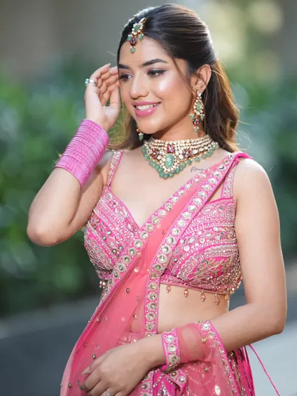 A close-up on the details of the pink lehenga, highlighting the beautiful choker set with green accents. I help you style your rental outfit perfectly.