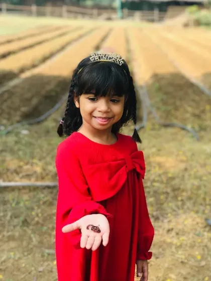 The same birthday girl showing her bravery and curiosity by holding an earthworm in her hand.