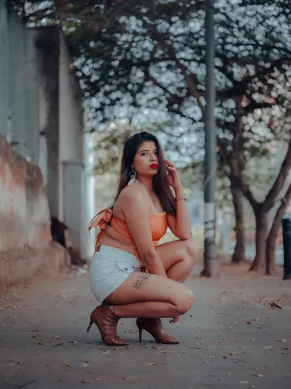 An urban portrait with a low-angle shot to create a dynamic perspective. The model's pose and the blurred background of trees and streetlights give this a classic street style feel.