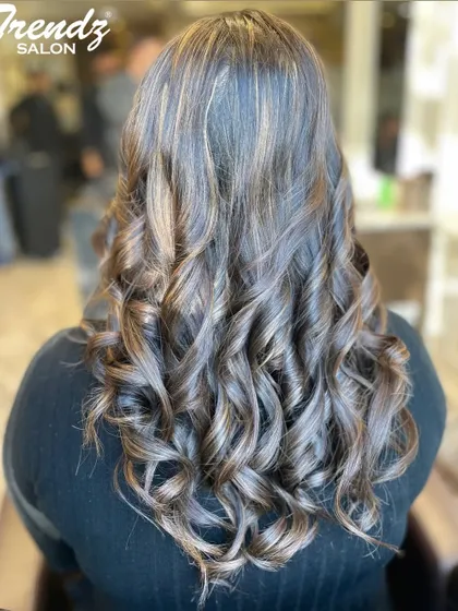 This client's hair is a perfect example of a cool-toned balayage. The ash and blonde highlights are expertly blended and styled into loose, glamorous curls.