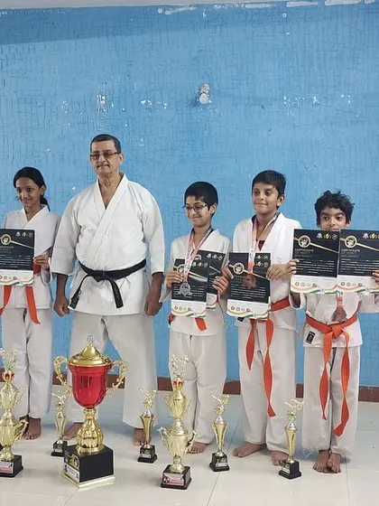 A proud moment for our sensei with students from the Silicon City dojo, displaying their individual trophies and the overall championship cup from a recent tournament.