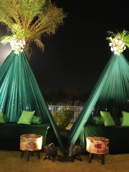 A cozy and chic seating arrangement for a Mehendi night, featuring green teepee-style tents with comfortable cushions.