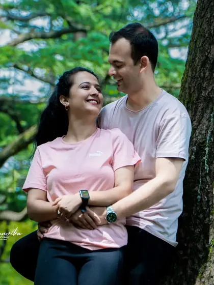 A sweet and romantic moment between a couple, captured in a natural forest setting. The genuine smiles and loving embrace say it all.