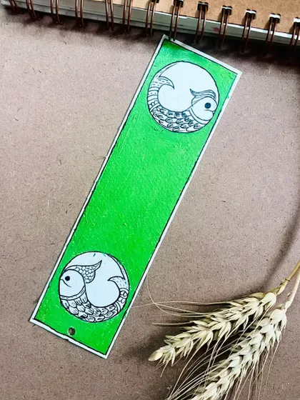 A simple yet elegant Madhubani bookmark with a green background and fish motifs.