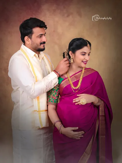 An intimate moment between a couple during their traditional indoor maternity shoot. The husband-to-be lovingly places a flower in his wife's hair.