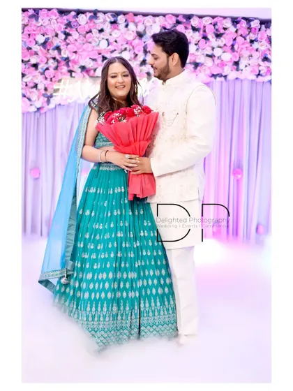 A sweet portrait of the newly engaged couple, holding the bouquet of roses against a backdrop of pink flowers.