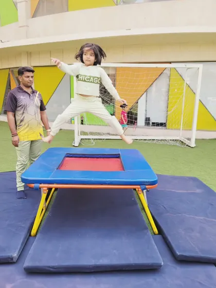 A young camper leaps with enthusiasm on the trampoline during a guided gymnastics session. These activities are fundamental for developing core strength, balance, and spatial awareness in a fun, engaging way.