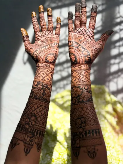 A closer look at the forearm details of a bridal design, featuring architectural dome (gopuram) and paisley motifs.