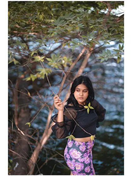 A portrait that blends the subject with nature. Her pose and the way she interacts with the branch create a connection to the environment.