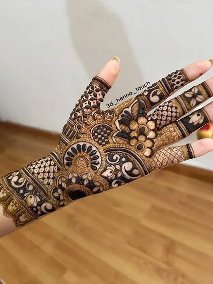 A detailed back-of-hand design that is both intricate and bold. The combination of a central mandala, net patterns, and floral motifs creates a stunning effect.
