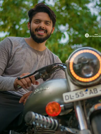 This portrait combines a smiling subject with a focus on the custom headlight of his Royal Enfield. It's a great way to create a lifestyle photo that highlights both the person and their passion.