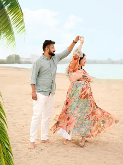 A joyful, candid moment of a couple dancing on the beach, with the colorful dress flowing in the breeze.