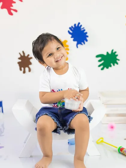 This little one's happy smile says it all. The colorful paint splatters on the background create a dynamic and festive atmosphere.