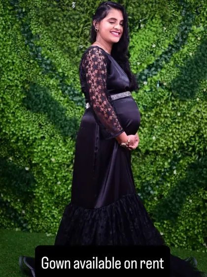 A chic and modern maternity look with this black satin gown featuring lace sleeves. It's a sophisticated choice for an indoor or outdoor shoot.
