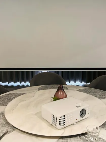 A short throw projector placed on a dining table, ready to create a personal cinema. This demonstrates the flexibility of modern projectors, allowing you to set up a big screen experience almost anywhere.