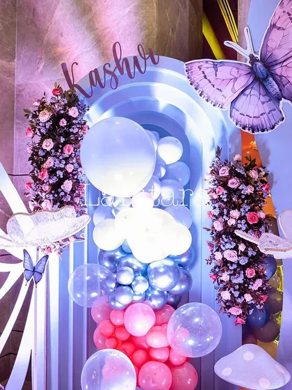 A decor detail featuring large butterfly props and a balloon arrangement, adding to the magical atmosphere.