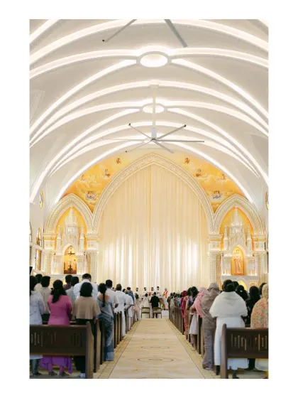 A wide shot of a grand church during a wedding ceremony. The beautiful architecture and the congregation of guests create a sense of scale and community in this sacred space.