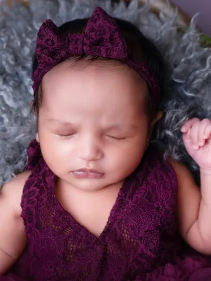 Royalty in rich purple. This newborn girl looks absolutely regal in a deep wine-colored dress, showcasing our ability to work with bold and beautiful color palettes.