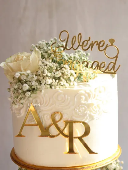 A close-up of the custom topper and delicate floral details on this stunning engagement cake.
