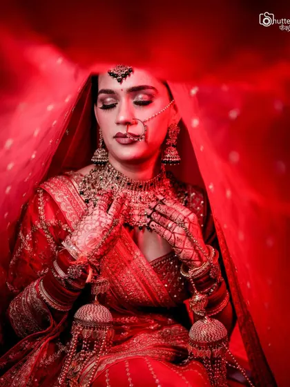 A powerful bridal portrait using a vibrant red veil to create a frame. The dramatic lighting and the bride's serene expression make this a truly artistic shot.