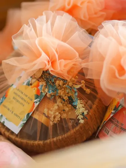 A close-up of a party favor, showing the beautiful wrapping with delicate dried flowers and a personalized "Thank you for showering us with love" tag.