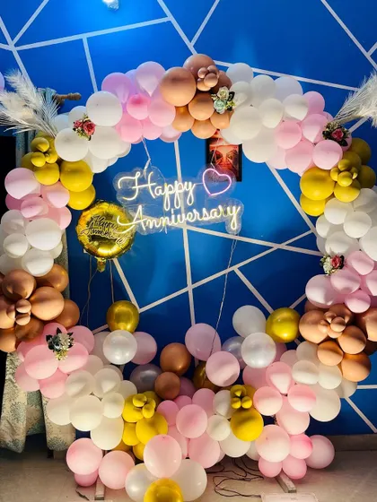 A close-up of the anniversary balloon ring, showing the detailed flower-like balloon clusters and the warm glow of the neon sign.