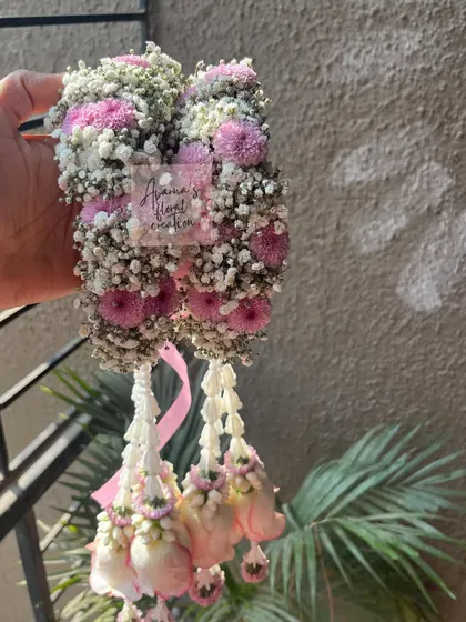 A close-up of a floral kaliree made with pink chrysanthemums, baby's breath, and hanging rosebuds. This shows the dense, textured top part of the accessory.