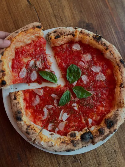 Taking the first slice of our Marinara pizza. It's a vegan delight.