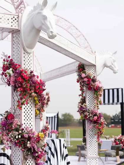 White trellises decorated with horse-head motifs and cascading floral arrangements. These structures added a touch of equestrian elegance to the polo-themed event.