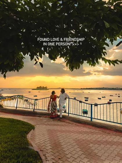 Finding love and friendship in one person is a beautiful thing. This shot, framed by the trees overlooking the water, captures a quiet, conversational moment during a lakeside couple photoshoot.