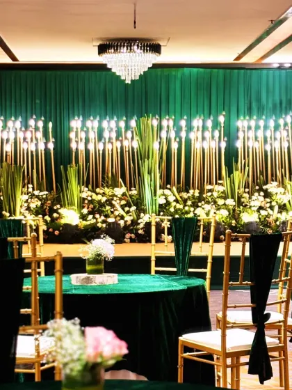A wider view of the emerald green Sangeet decor, showing the guest seating with matching green tablecloths and elegant Chiavari chairs.