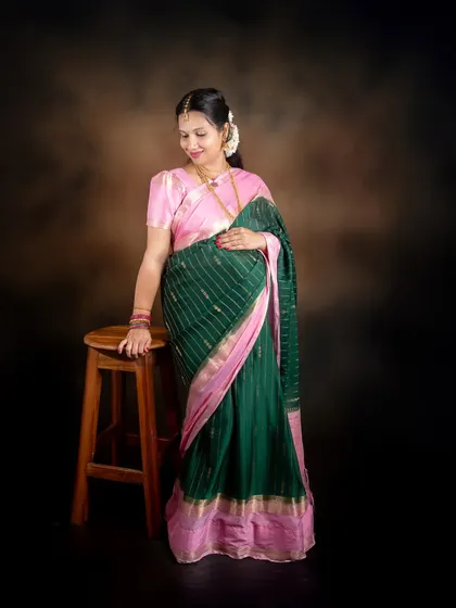 A full-length solo portrait of a mom-to-be in a beautiful saree, captured against a classic mottled brown backdrop in our studio.